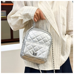 Detailed view of silver quilted backpack featuring a metallic finish and chain strap details