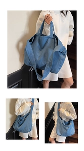 Detail view of large blue denim tote bag showing double stitching and wide shoulder strap