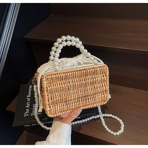 Detailed macro view of woven straw bag with pearl handle and inner drawstring lining