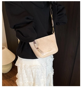 Detail of beige vintage crossbody bag with gold logo and decorative tassel zipper