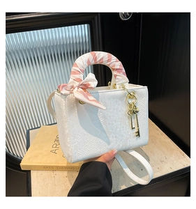 Détail du sac à main blanc motif écailles avec poignée en foulard de soie et pendentif clé dorée