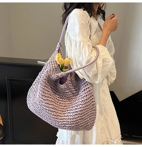 Detail of purple hand-crocheted straw shoulder bag with elegant hobo design for beach vacation