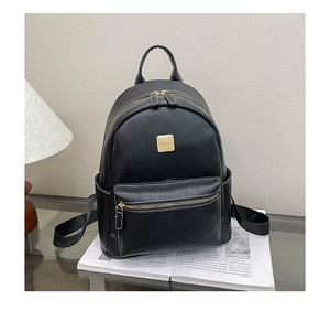Detail of a black faux leather backpack featuring contrast stitching and gold-tone logo plate