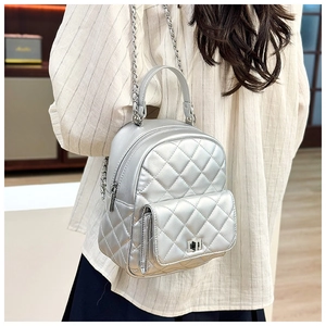 Close-up of silver quilted backpack with chain straps and metal twist lock detail