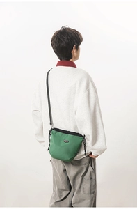 Close-up of green checkered crossbody bag with drawstring closure and logo patch