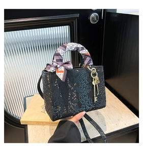 Détail du sac à main noir à texture écailles avec poignée en foulard et pendentifs dorés