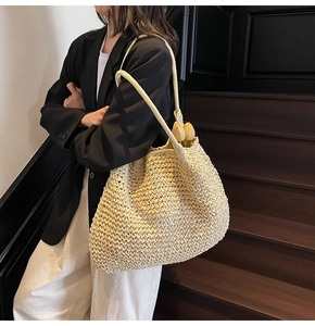 Close-up of the woven straw texture and slender handles on this beige tote beach bag