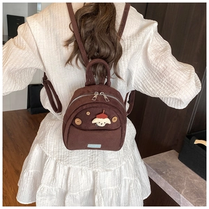 Dettaglio mini zaino in pelle scamosciata marrone con patch a forma di cane e bottoni in legno