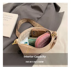 Detail view showing the spacious interior of a beige leather crossbody bag with items