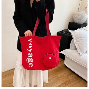 Détail du sac cabas en toile rouge avec texte voyage blanc et pochette ronde à fermeture éclair