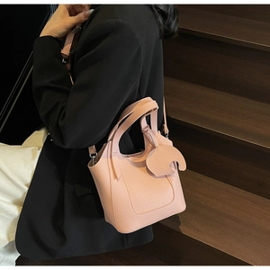 Detailed close-up of pink lychee grain leather bucket bag with moon-shaped charm accessory