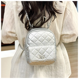 Silver quilted mini backpack with metal chain straps worn by model against a neutral wall