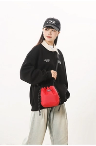 Red plaid nylon drawstring bucket bag worn cross-body by a model in casual style