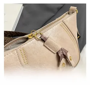 Detail shot of the beige textured leather bag with gold hardware and woven strap accents