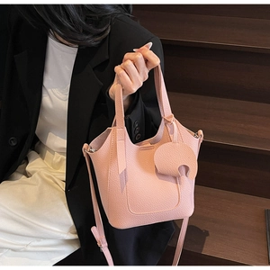 Close-up of pink lychee textured leather bucket bag with silver hardware and shoulder strap