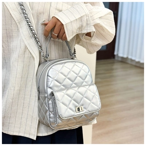 Detail of silver quilted mini backpack featuring metallic finish and chain strap