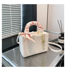 Détail d'un sac blanc à motif serpent avec poignée en soie et pendentif clé dorée élégant