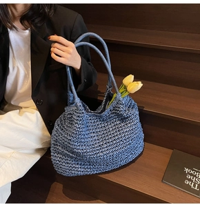 Blue woven straw tote bag with fresh tulips placed inside on dark wooden stairs
