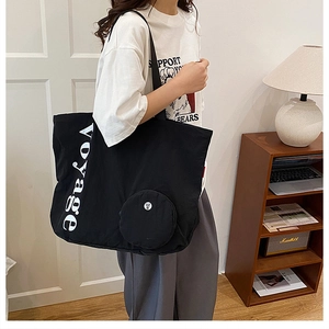Détail d'un grand sac cabas en toile noire avec imprimé Voyage et petit porte-monnaie