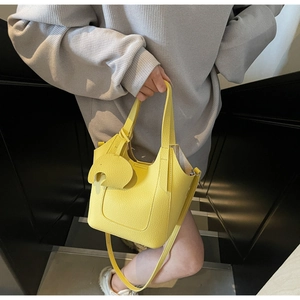 Detail of yellow lychee grain leather handbag with elephant charm and shoulder strap