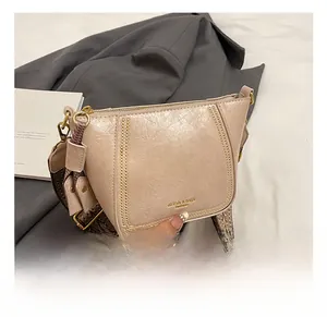 Detail of nude beige leather dumpling bag with woven strap and gold chain accent