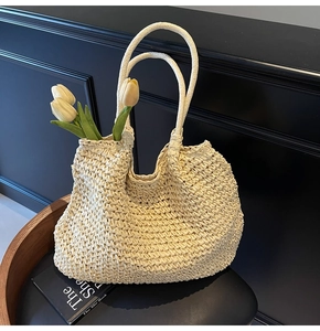 Close-up of cream woven straw tote bag with textured knit details and tulip decor