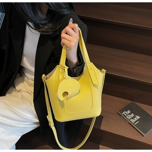 Close-up of bright yellow litchi texture bucket bag with cute elephant charm and strap