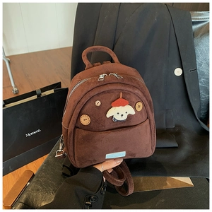 Dettaglio di un mini zaino in pelle scamosciata marrone con patch di cucciolo e bottoni