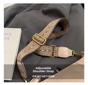 Detail of adjustable wide woven shoulder strap with golden metal buckle for crossbody bag
