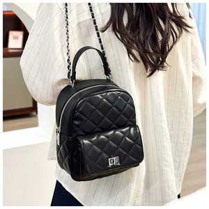 Detailed view of black quilted mini backpack with chain strap on a fashion model