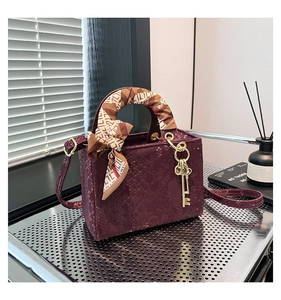 Détail du mini sac bordeaux peau de serpent avec foulard en soie et pendentif doré