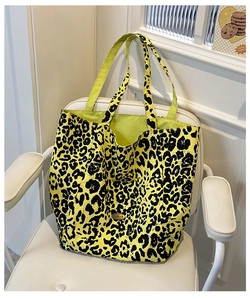 Detailed view of large leopard print tote bag with green lining on a modern chair