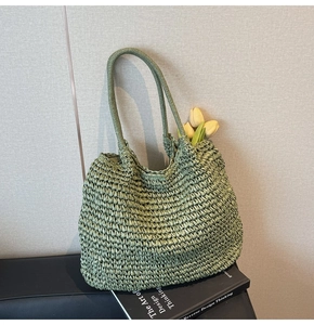 Close-up of green hand-woven straw tote bag texture and slim shoulder straps