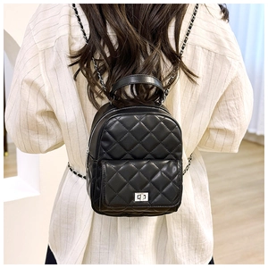 Detail of black quilted leather backpack with silver chain straps shown on model