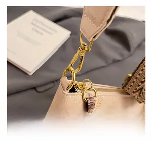 Detail of premium gold metal hook on beige pebbled leather bag with woven strap