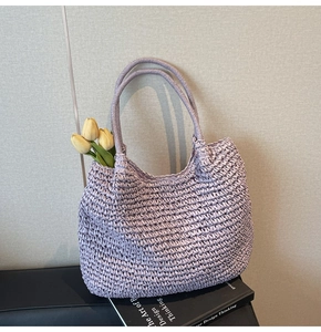 Detail view of purple woven straw tote bag with intricate texture and hobo silhouette