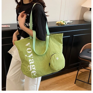 Détail du sac fourre-tout en nylon vert avec imprimé voyage et petite pochette assortie