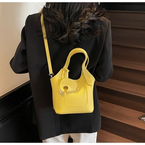 Macro detail of vibrant yellow litchi pattern leather bucket bag with cute elephant charm