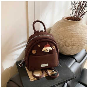 Dettaglio mini zaino in finta pelle scamosciata marrone con patch di cane e bottoni in legno