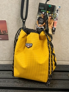 Bright yellow checkered drawstring crossbody bag with adjustable black shoulder strap