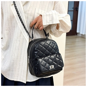 Detail of black quilted mini backpack with silver metal turn-lock and chain strap