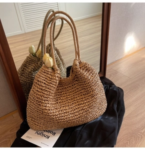 Close-up of hand-woven straw tote bag with long handles and natural texture on silk fabric