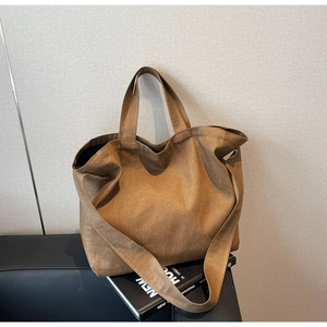 Detail of minimalist dark brown canvas tote bag featuring textured fabric and wide shoulder strap