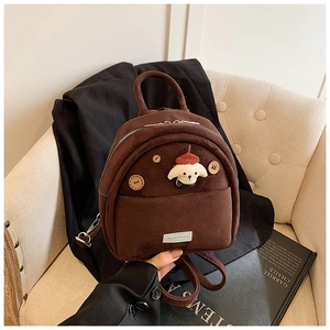 Dettaglio di un mini zaino in pelle scamosciata marrone con bottoni in legno e peluche