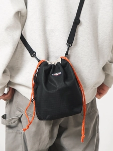 Crossbody black checkered drawstring bucket bag with vibrant orange cord and adjustable strap