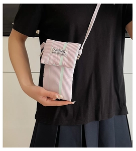 Close-up of striped crossbody phone bag with Fashion Instinct label and pink stripes