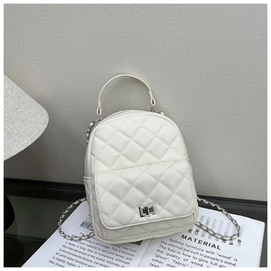 Close-up of white quilted mini backpack with silver twist lock and chain strap detail
