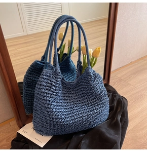 Detailed close-up of navy blue straw tote bag with fine woven texture and sturdy handles
