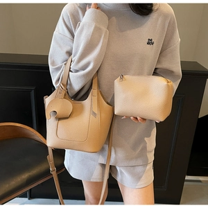 Detail view of beige lychee grain leather tote set with an elephant charm and small pouch