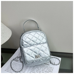 Detail view of silver quilted backpack featuring chain straps and metallic twist lock clasp